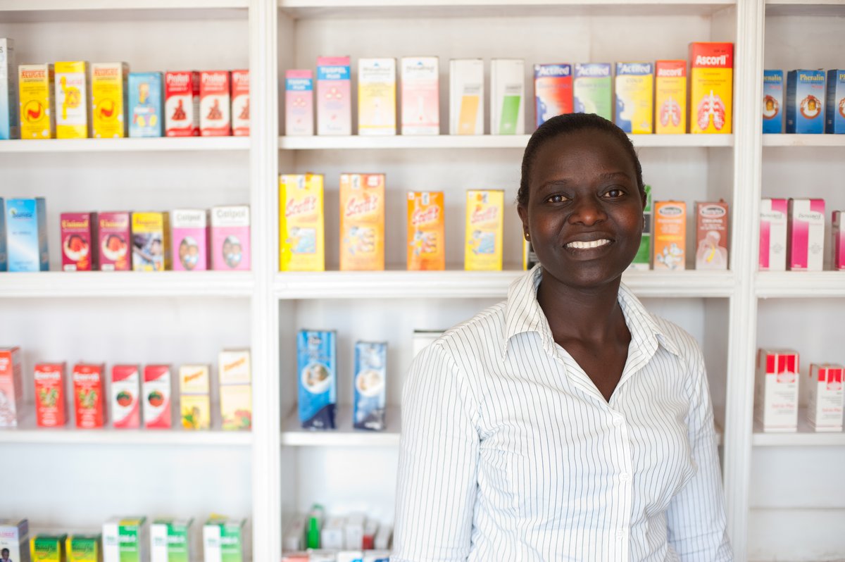 Woman standing in front of shelves of medicine in a chemist shop.