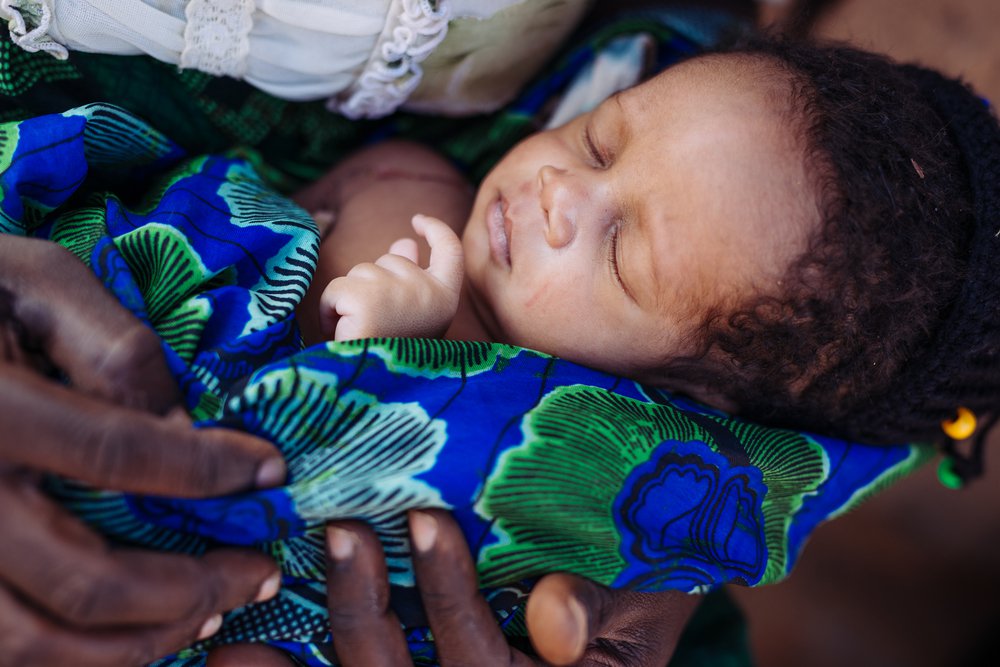 In Sinafala village, an infant sleeps on her mother's lap