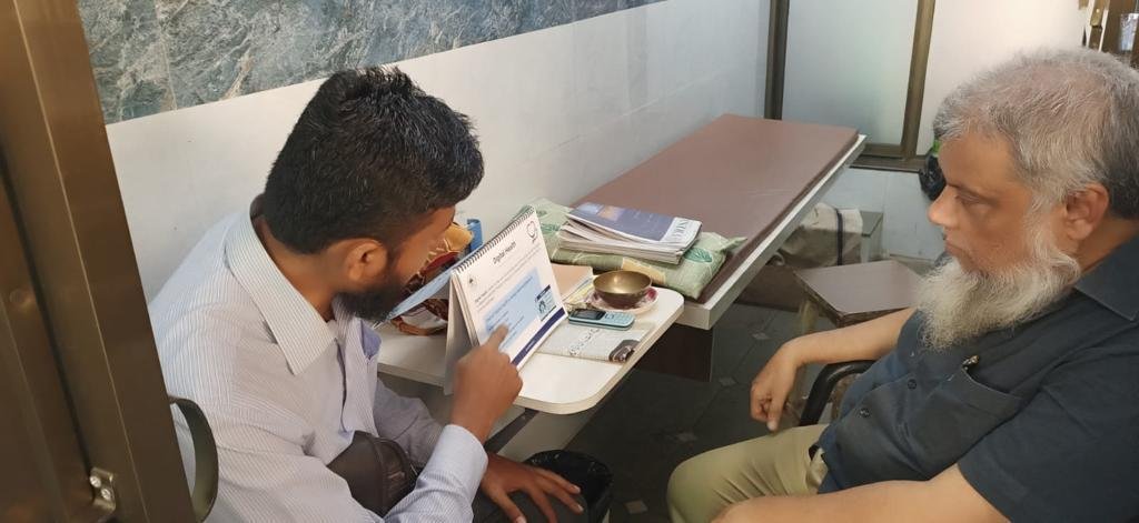 A project team member explains the benefits of digital registration to a private doctor through outreach material. Photo: PATH.