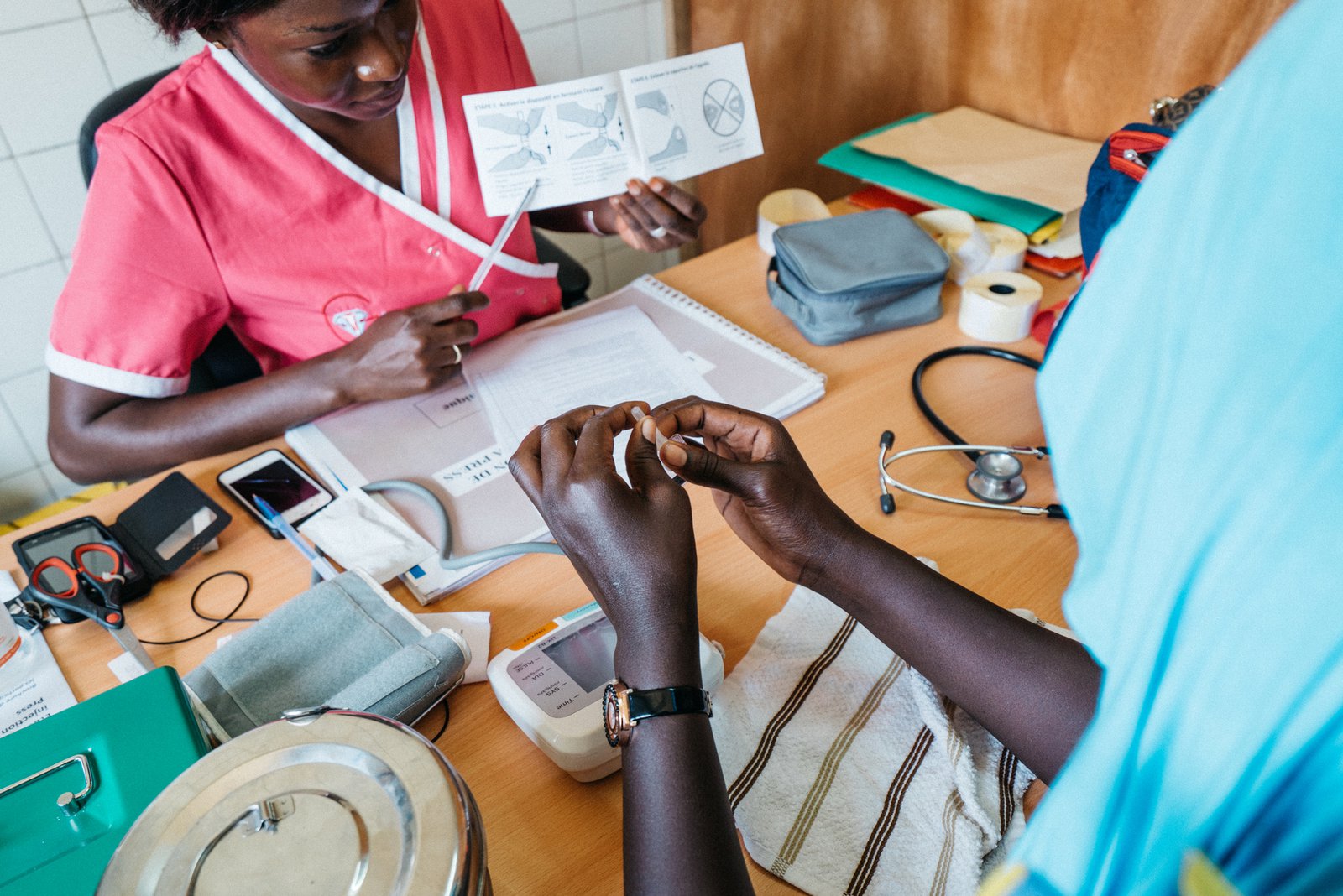 Aminata Gaye, 29, (in pink) explains to Mossan Faye, 21, how to self-inject the contraceptive Sayana® Press at the Dominique Health Center in Pikine, Senegal. PATH/Gabe Bienczycki.