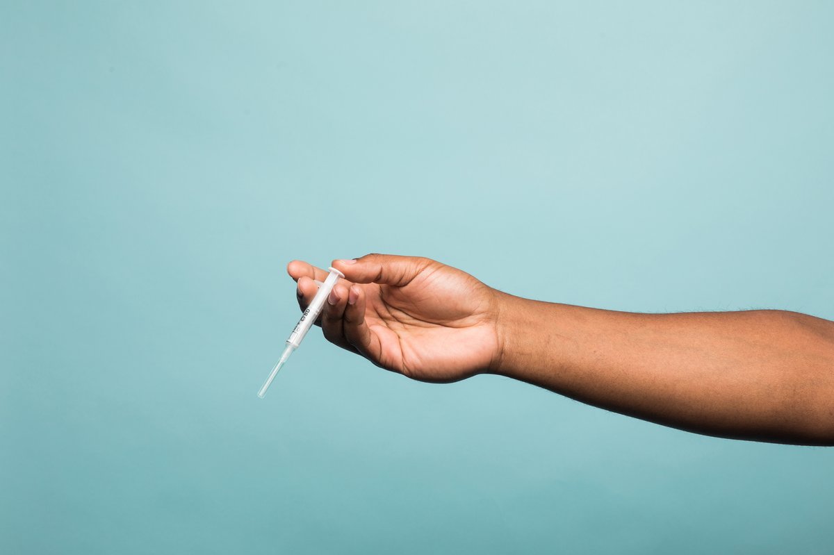 Hand holding syringe with blue background