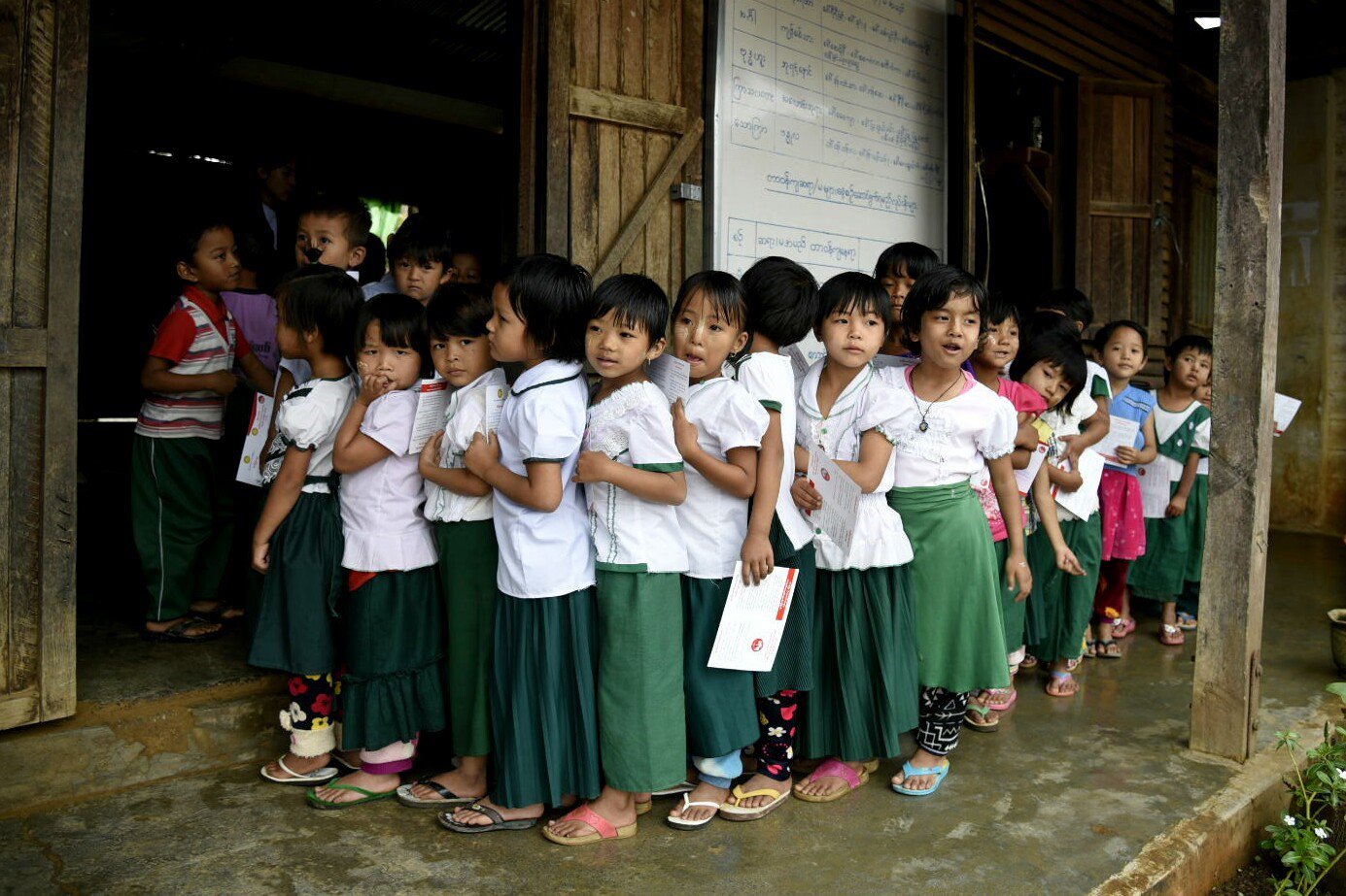 Children waiting in line, holding their immunization records.