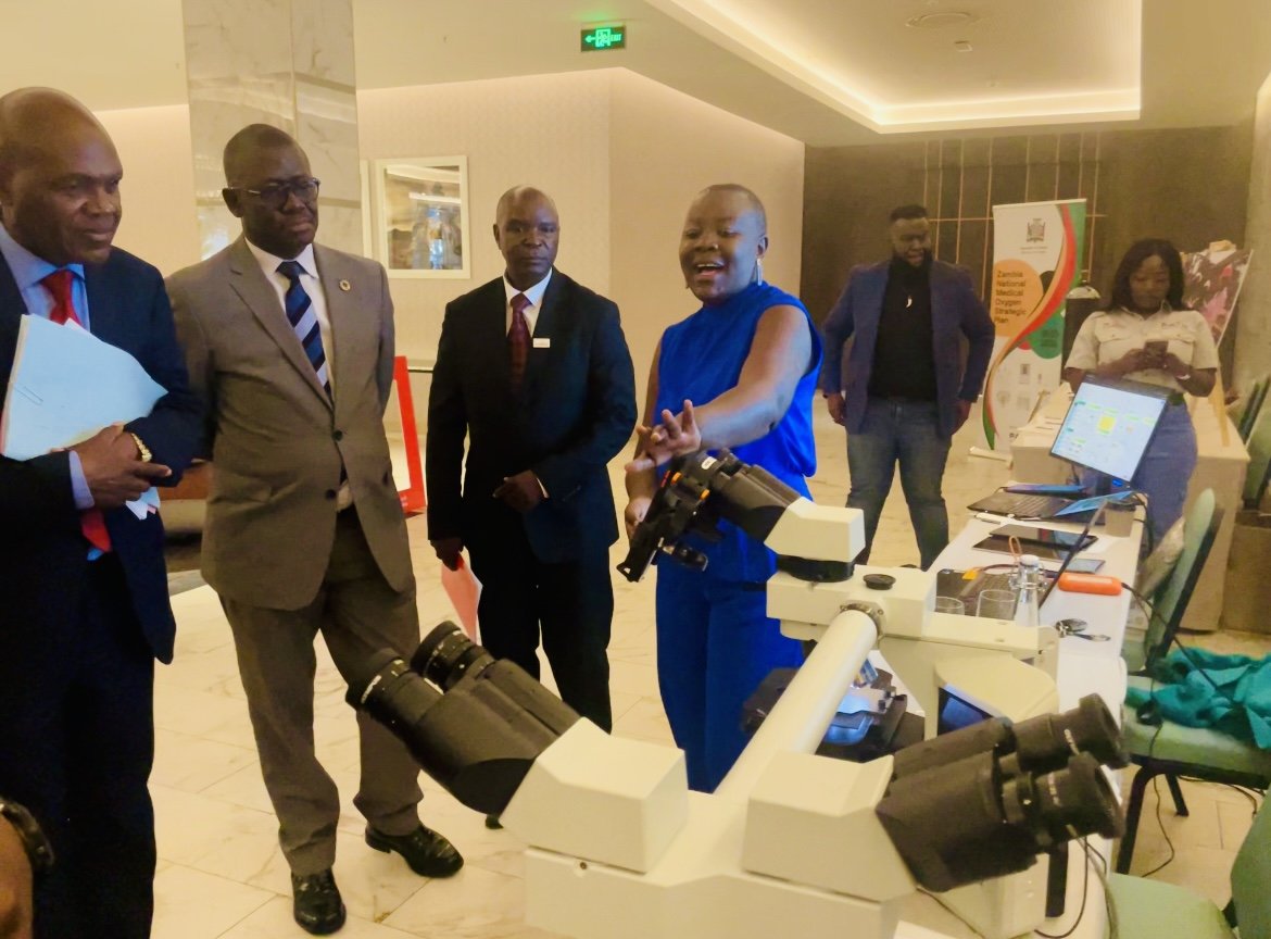 PATH Zambia Mulenga Mwenda-Chimfwembe (in blue dress) explaining Zambia lab capabilities during the 20th anniversary showcase. Photo: PATH/Charles Wanga.