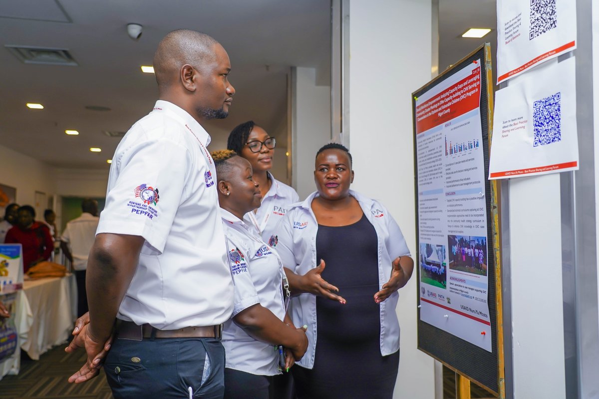 Trizah Ouma, PATH Program Officer, discusses her poster on supporting community health volunteers who serve as caseworkers for orphans and  children vulnerable to HIV in Migori County. Photo: PATH.