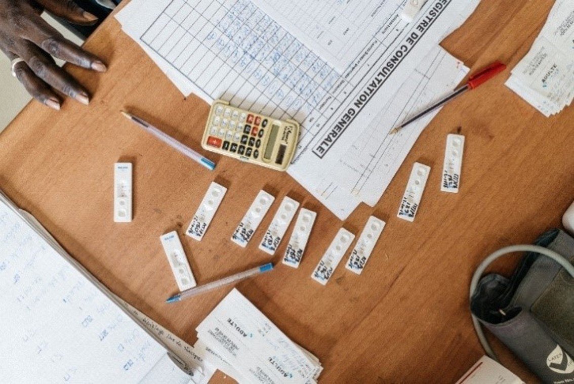 Rapid diagnostic tests for malaria cover the desktop of nurse Amadou Ngom at the Mbem Mbem health post in Senegal. Photo:PATH/Gabe Bienczycki