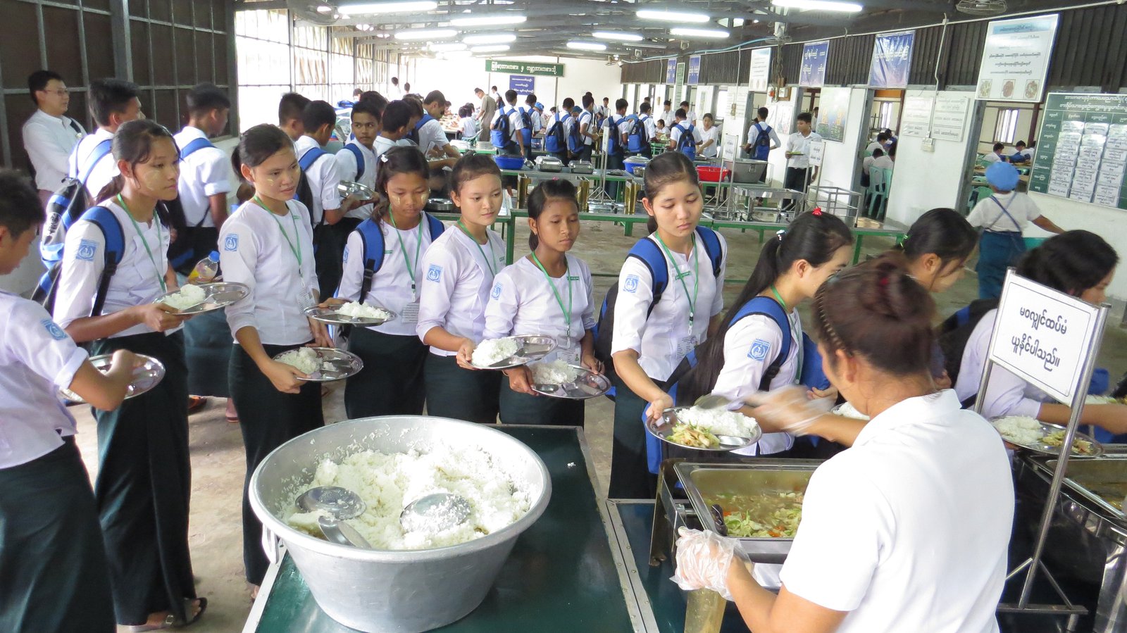 Students in uniform line up for lunches.