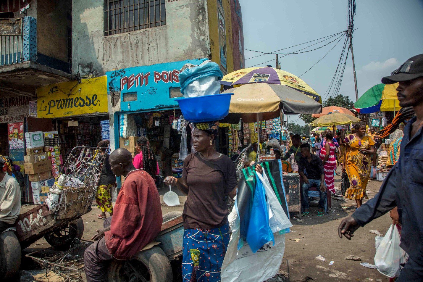 People walk through a busy, crowded street lined with umbrellas.