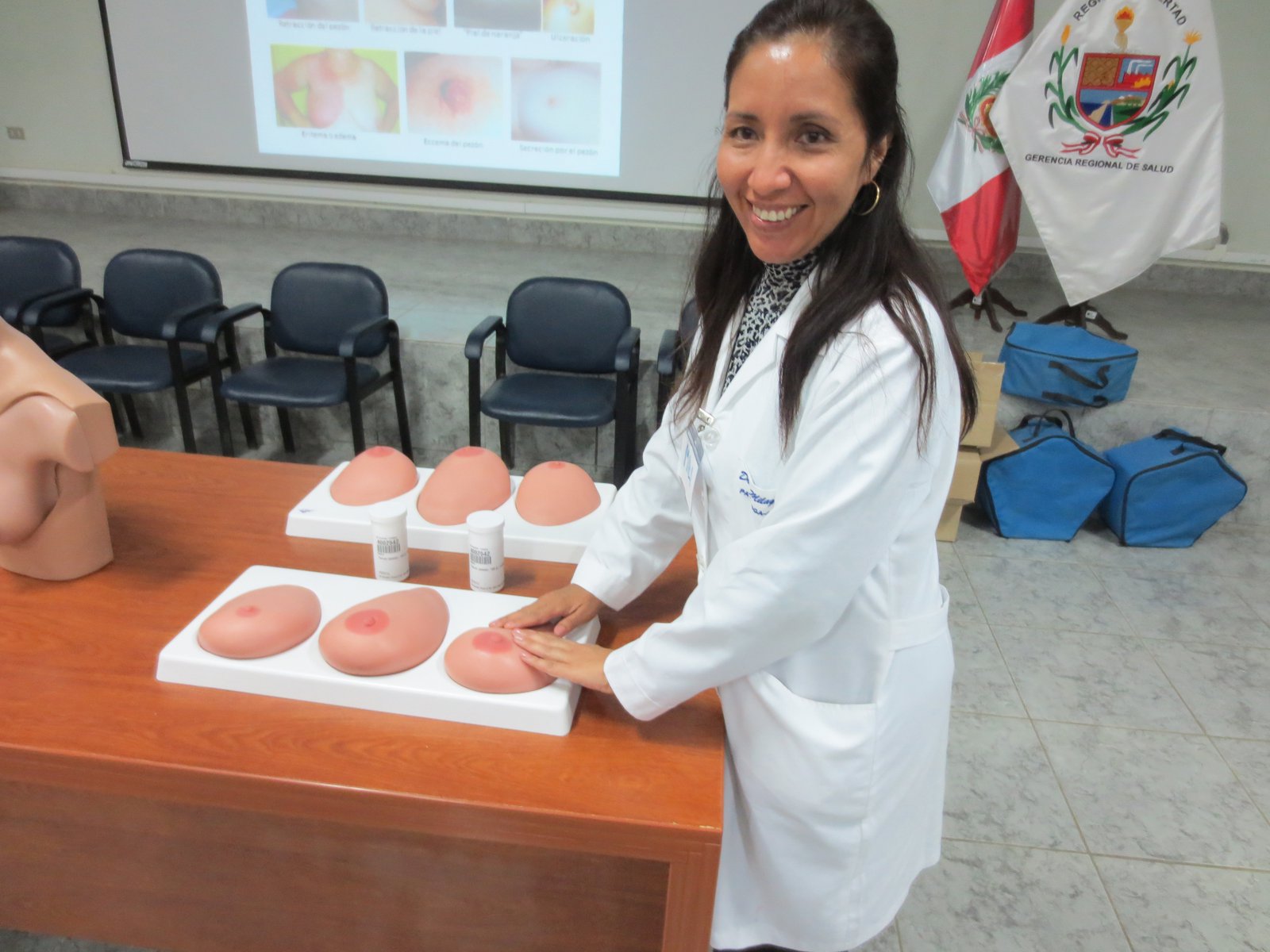 A woman in a lab coat practices breast cancer screening on synthetic breast models.