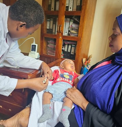 Joyce Nuhu, a clinical officer from Nguvumali Health Center in Tanga, attending to a sick baby using a handheld pulse oximeter. Photo: PATH/Olgah Odek