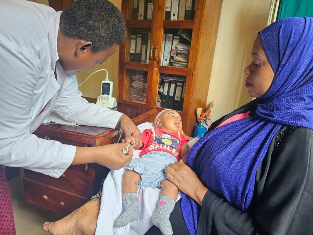 Joyce Nuhu, a clinical officer from Nguvumali Health Center in Tanga, attending to a sick baby using a handheld pulse oximeter. Photo: PATH/Olgah Odek