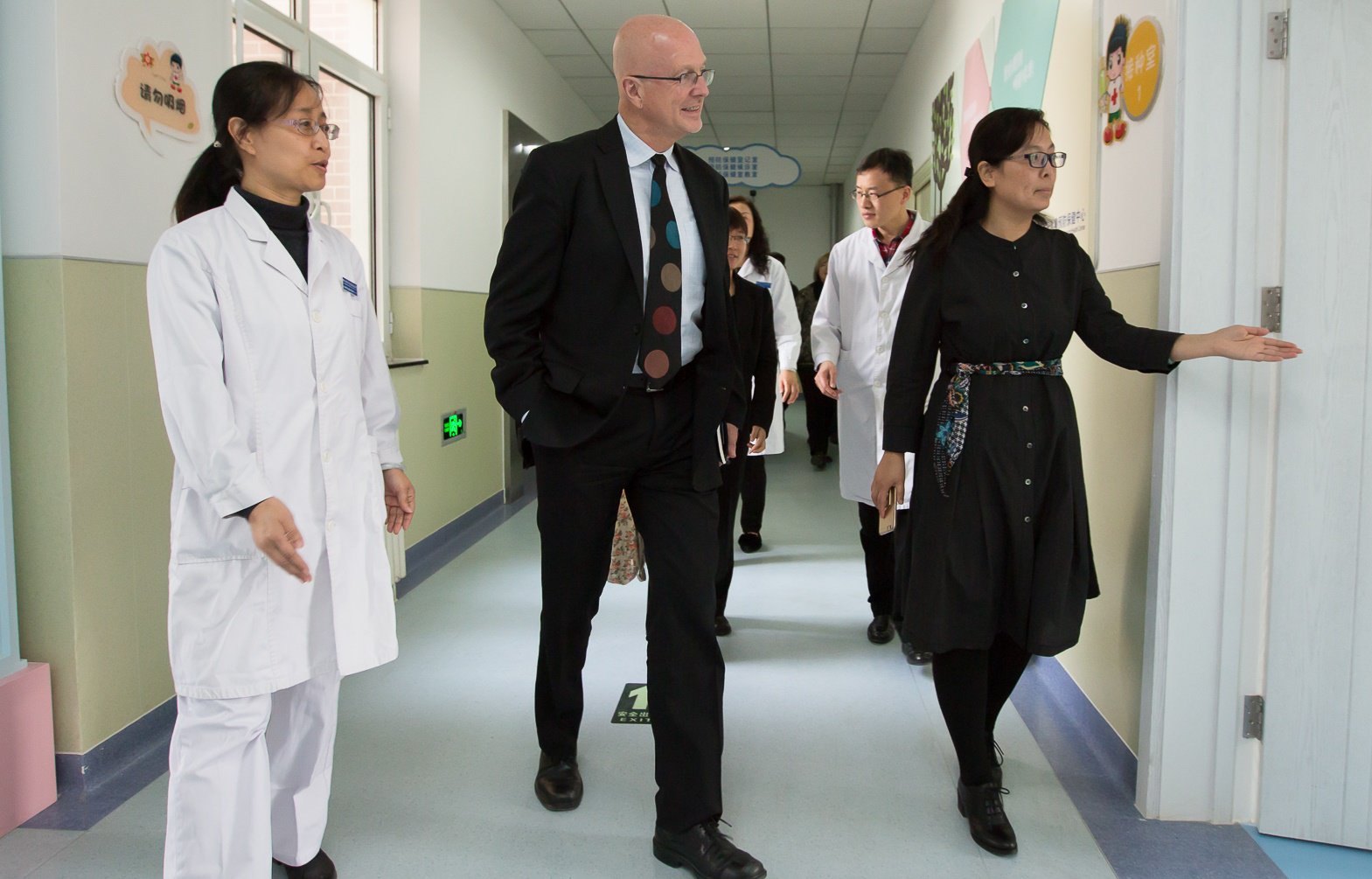 Steve Davis walks down a hallway with several people at the Daxing District Immunization Center.