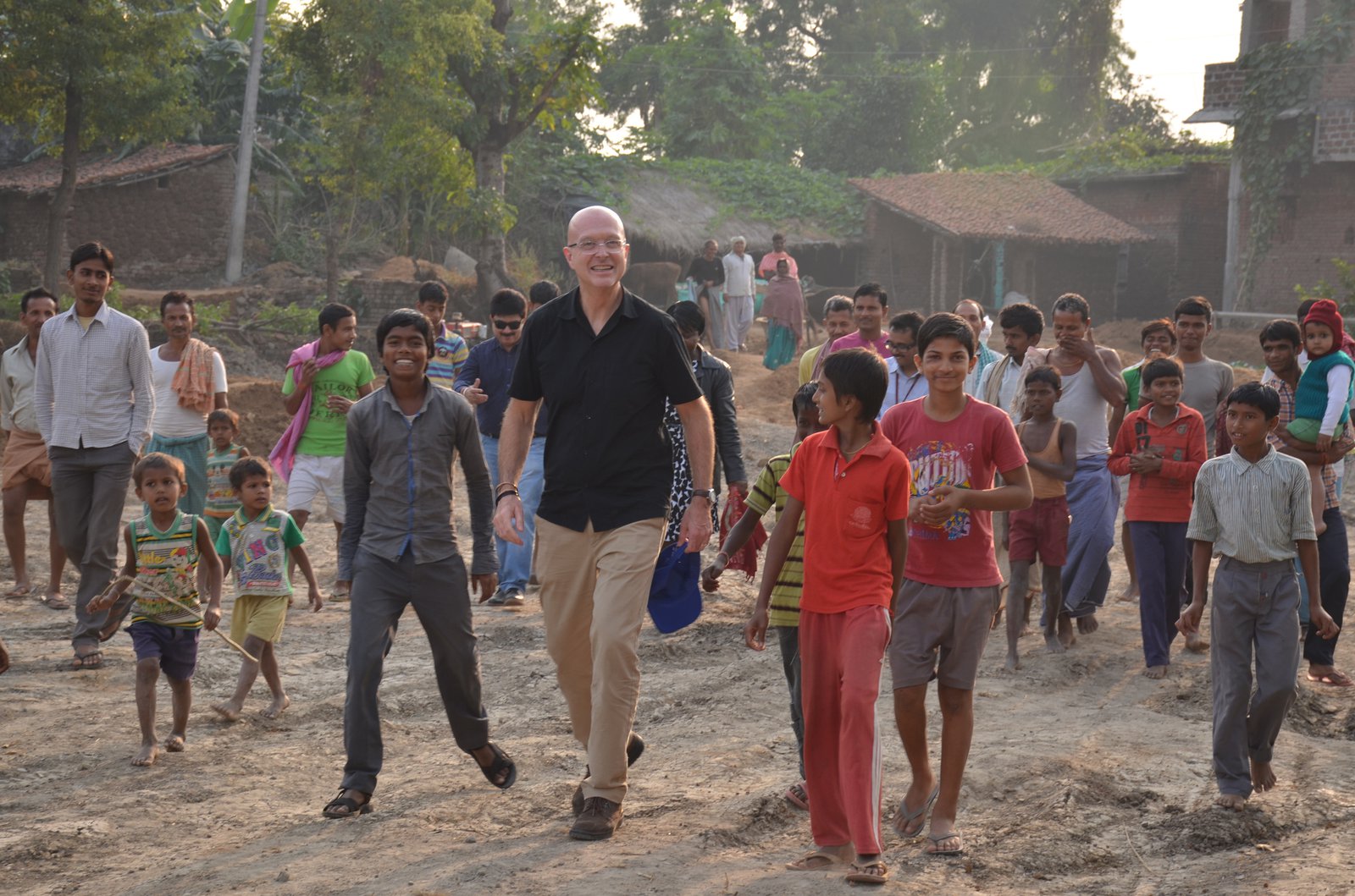 Steve Davis walks through a village in India with a group of children.